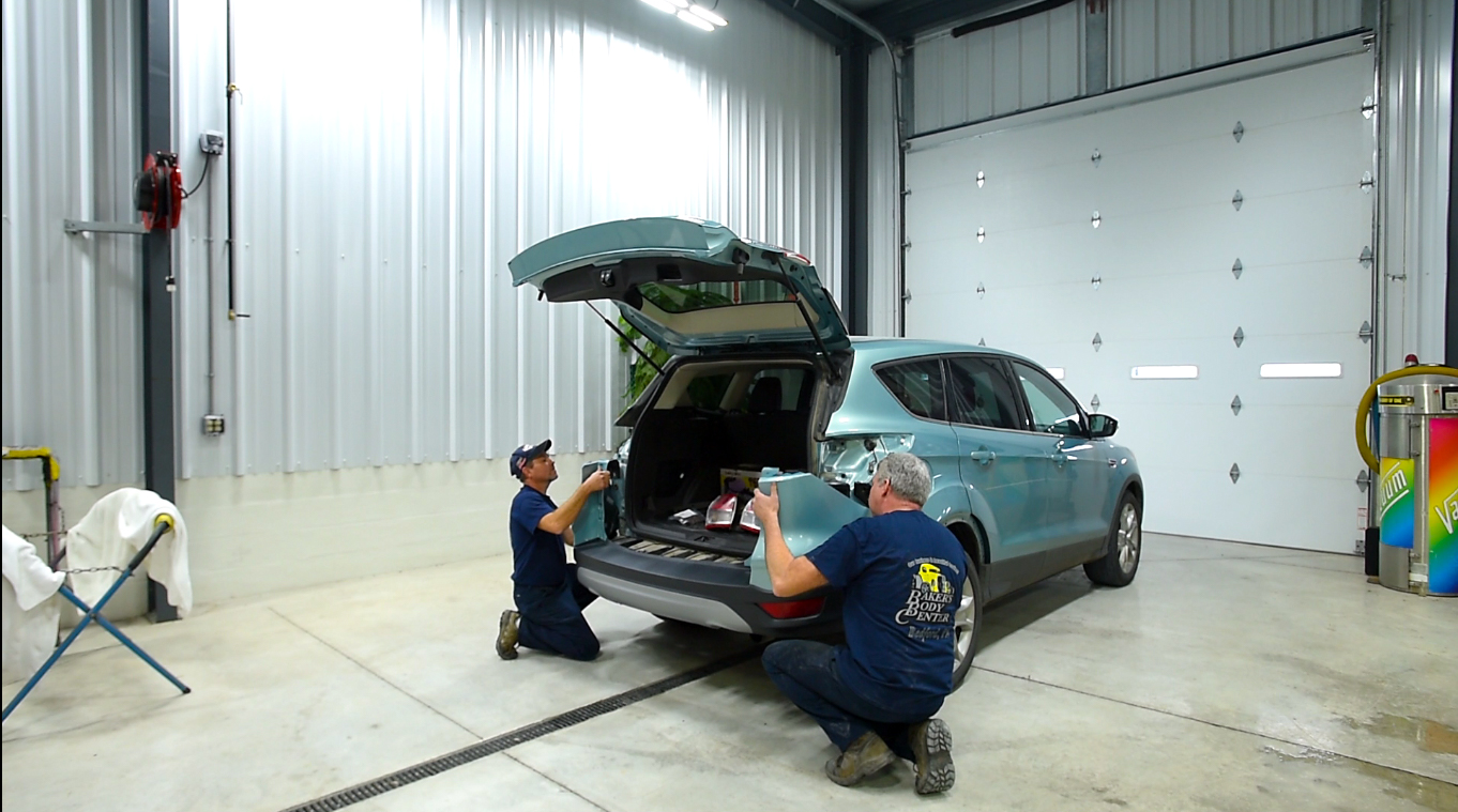Baker's Body Center employees fixing the fender of an SUV