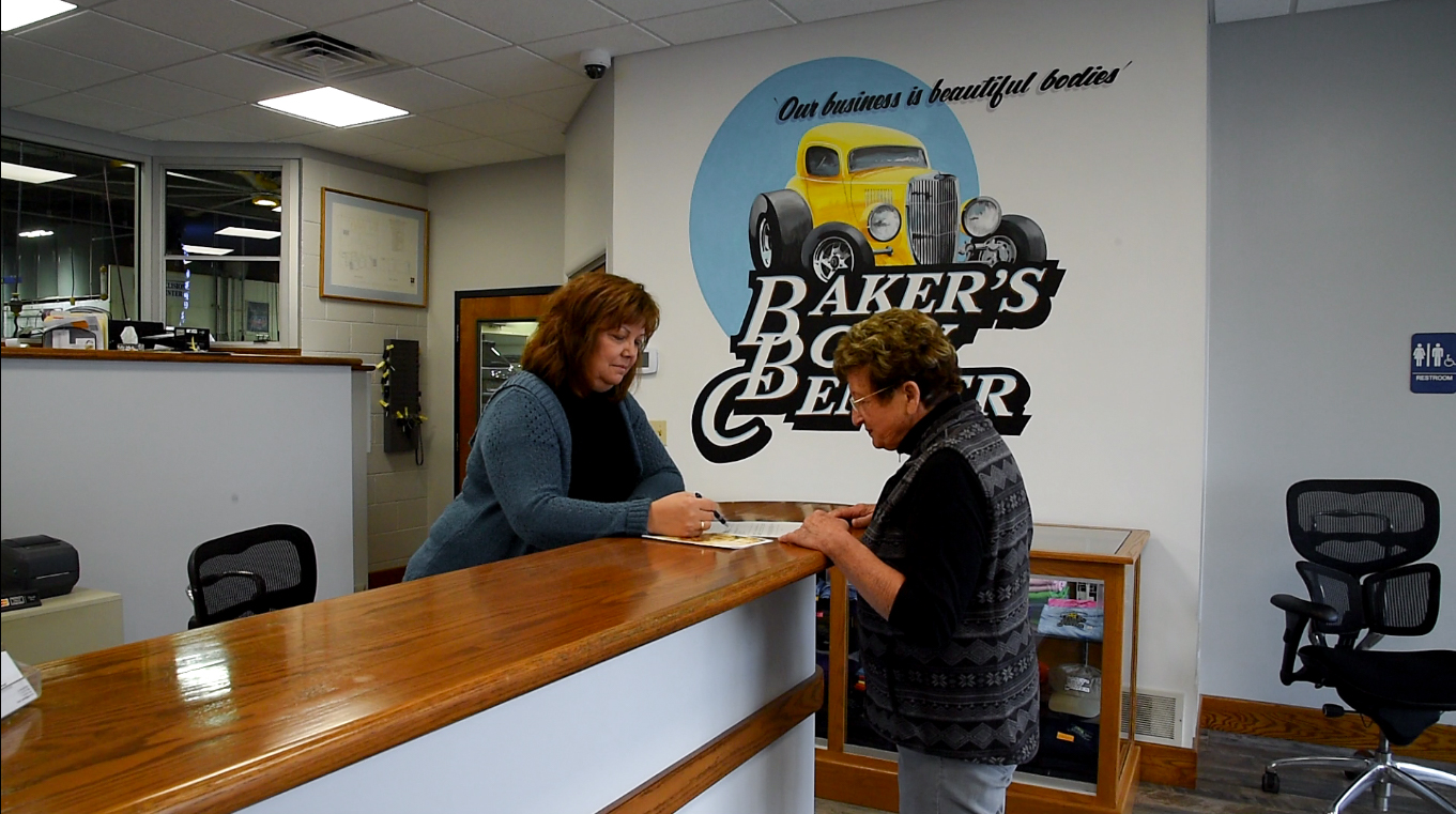 Baker's Body Center receptionist showing paperwork to a client